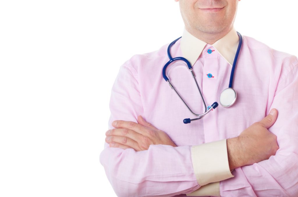 Doctor with a stethoscope stands with crossed arms on white back